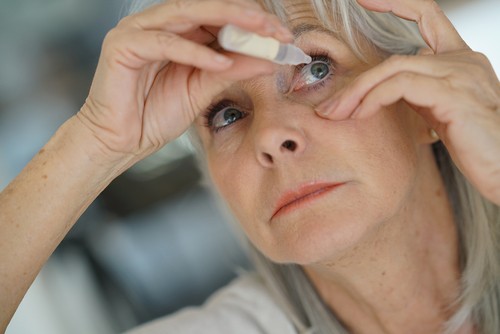 Woman using an eyedropper to treat glaucoma