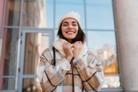 Woman wearing a winter coat, scarf and hat in the city.