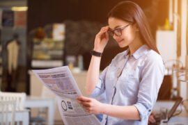 Woman with glasses reading a newspaper