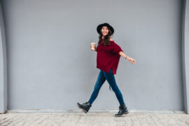 Woman wearing a hat walking with a drink in hand